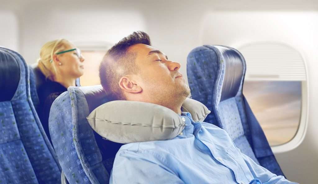 Man sleeping on a plane, how to sleep on a plane